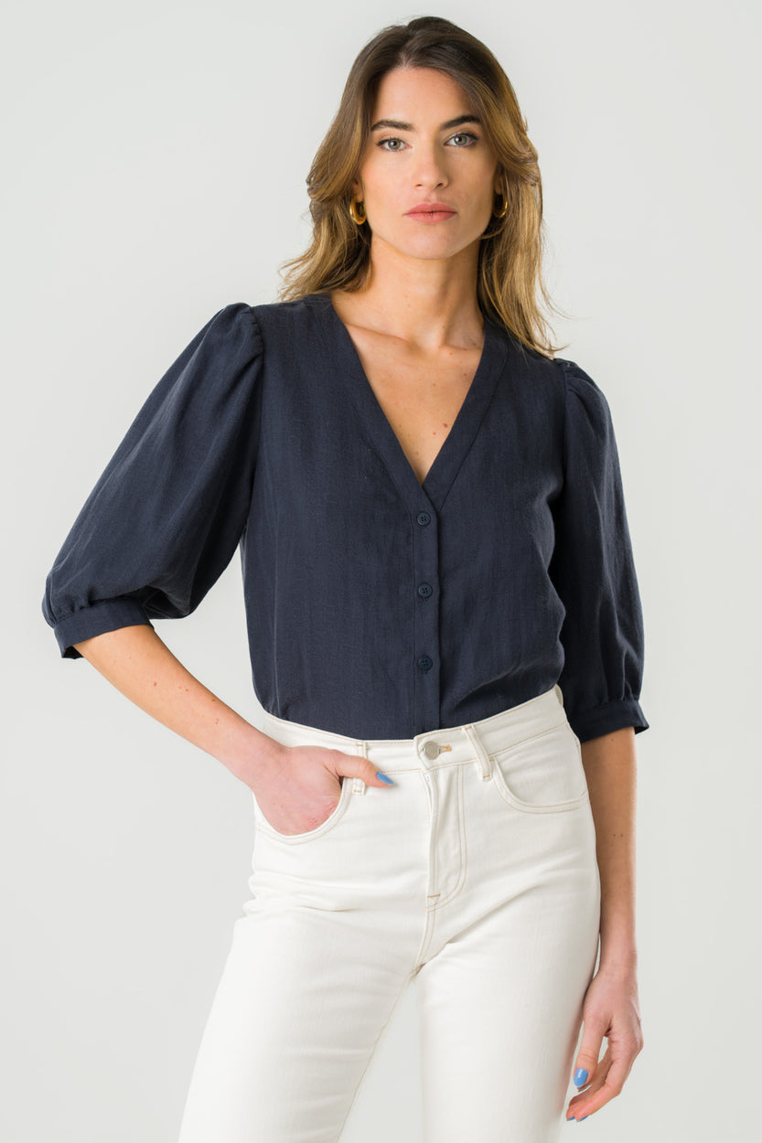 
                  
                    Blouse col V bleu marine avec manches bouffantes en Tencel, fabriquée en France, chic et durable.
                  
                