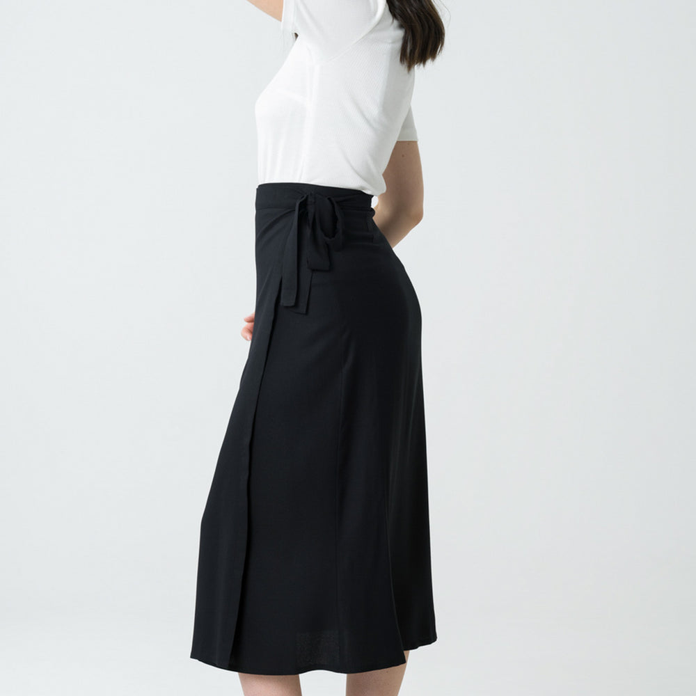 
                  
                    Jupe portefeuille noire mi-longue en viscose Ecovero, fabriquée au Portugal, avec une coupe asymétrique et un tissu doux pour une silhouette moderne et responsable.
                  
                